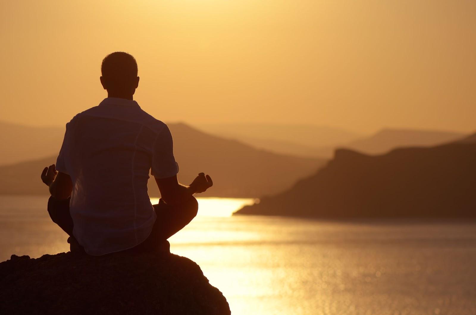 Man meditating at sunset